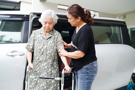 Caregiver help Asian elderly woman disability patient get in her car, medical concept.