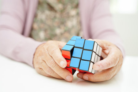 Bangkok, Thailand - May 15, 2022 Asian elderly woman playing Rubik cube game to practice brain training for help dementia prevention and Alzheimer disease.のeditorial素材