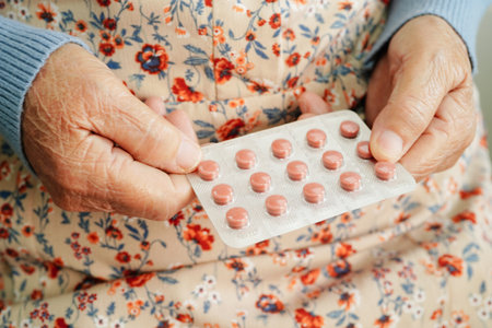 Asian elderly woman holding pill drug in hand, strong healthy medical concept.の写真素材