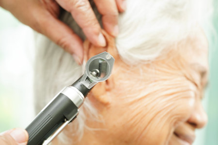Otolaryngologist or ENT physician doctor examining senior patient ear with otoscope, hearing loss...