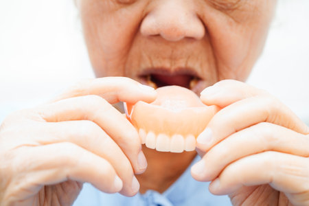 Asian senior woman patient wearing teeth denture into her mouth for chew food.