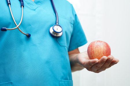 Asian Nutritionist holding apple healthy food for patient in hospital, nutrition and vitamin.の写真素材