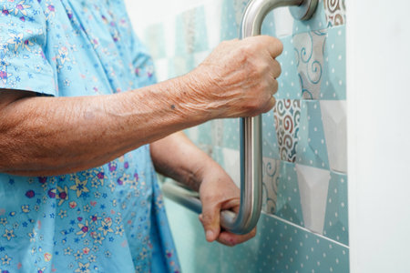 Asian elderly old woman patient use toilet support rail in bathroom, handrail safety grab bar, security in nursing hospital.の写真素材