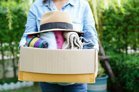 Volunteer collect cloth and hat in cardboard box to donate.