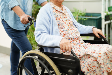 Caregiver help Asian elderly woman disability patient sitting on wheelchair in hospital, medical concept.の写真素材