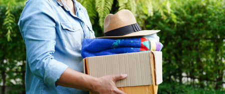 Volunteer collect cloth and hat in cardboard box to donate.