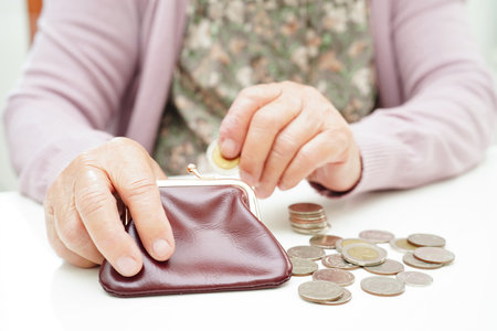 Retired elderly woman counting coins money and worry about monthly expenses and treatment fee payment.の写真素材