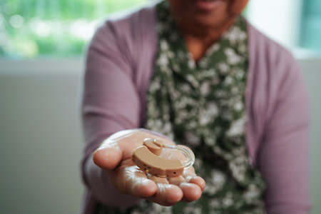 Asian senior woman patient using hearing aid in ear to reduce hearing loss problem.の写真素材