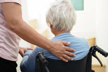 Asian senior woman on wheelchair with caregiver help support walking down the stairs prevent accident, slip and fall at home.の写真素材