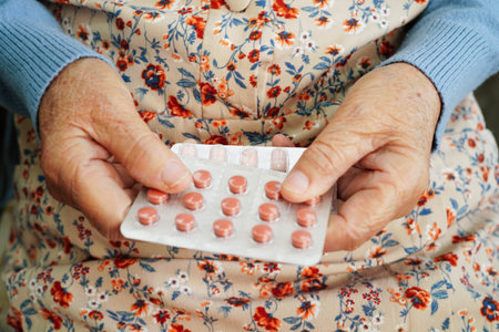 Asian elderly woman holding pill in hand, strong healthy medical.の写真素材