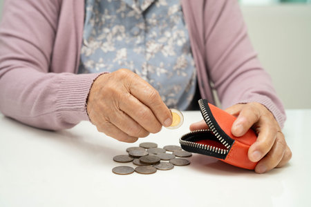 Asian senior or elderly old lady woman holding counting coin money in bag. Poverty, saving problem...