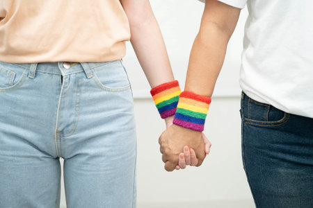 Asian LGBT couple woman holding hand wearing rainbow wristband.