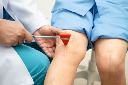 Asian doctor knock on knee reflex nerve for check and treatment senior patient in hospital.の写真素材