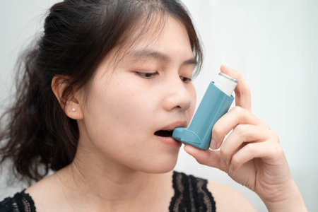 Asthma and chronic obstructive pulmonary disease COPD, Asian teenage using metered dose inhaler MDI.の写真素材