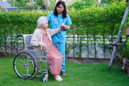 Doctor help Asian elderly woman disability patient walk with walker in park, medical concept.の写真素材