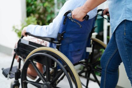 Caregiver help Asian elderly woman disability patient sitting on wheelchair in hospital.の写真素材
