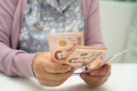 Retired elderly woman counting coins money and worry about monthly expenses and treatment fee payment.の写真素材