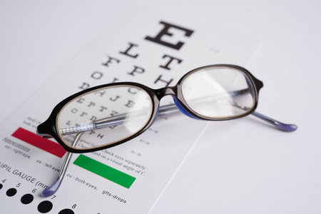 Glasses on eye exam chart to test eyesight accuracy of reading.
