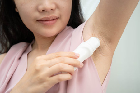 Asian young woman applying roll on deodorant reduce underarm sweat and odor after shower.