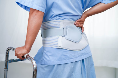 Asian senior pain back wearing elastic support belt with walker.
