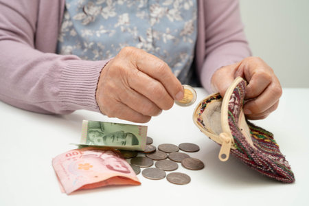 Asian senior or elderly old lady woman holding counting coin money in bag. Poverty, saving problem in retirement.の写真素材