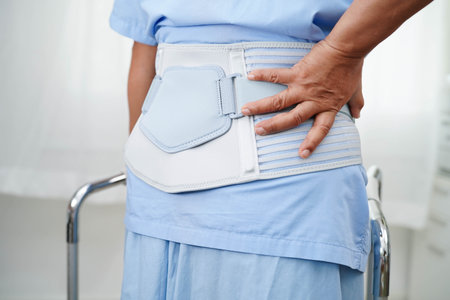 Asian senior pain back wearing elastic support belt with walker.の写真素材