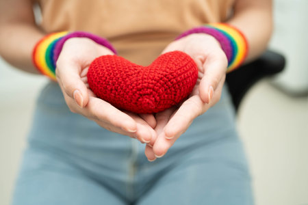 Asian woman holding LGBT heart with rainbow flag.