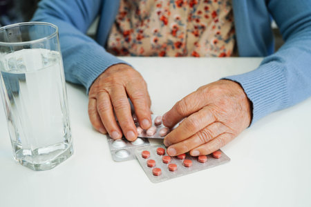 Asian elderly woman holding pill with water in glass, strong healthy medical.の写真素材