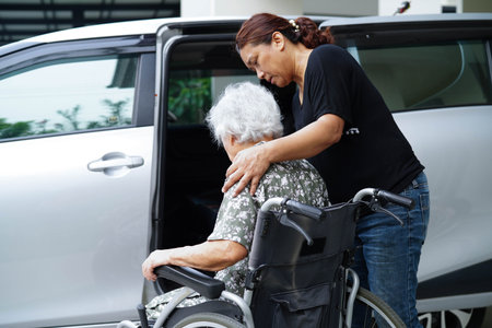 Caregiver help Asian elderly woman disability patient get in her car.