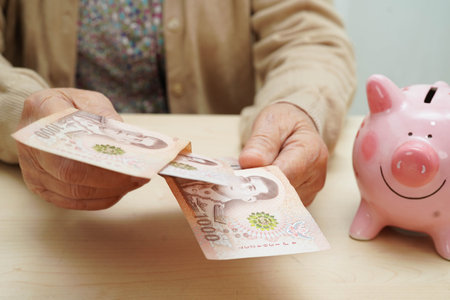 Retired elderly woman counting coins money and worry about monthly expenses and treatment fee payment.の写真素材