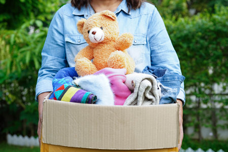 Volunteer collects cloth and doll in cardboard box to donate.の写真素材