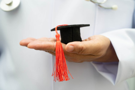 Asian woman doctor holding graduation hat in hospital, Medical education concept.の写真素材