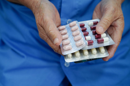 Asian elderly woman holding pill in hand, strong healthy medical.の写真素材