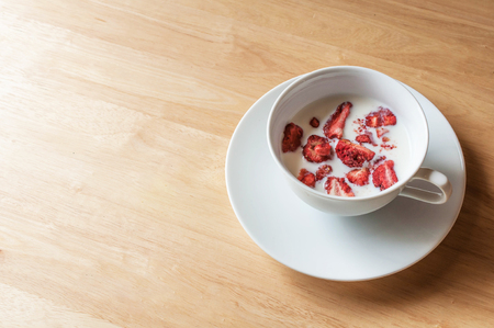 strawberry freeze dry in milk cup on wooden table close up with copyspaceの写真素材
