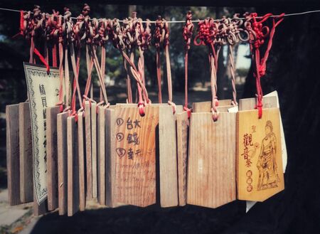 Wooden Chinese wishing tags hanging from red ribbonの写真素材