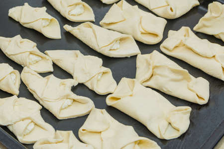 Cottage cheese rolls made from raw puff pastry, prepared for baking