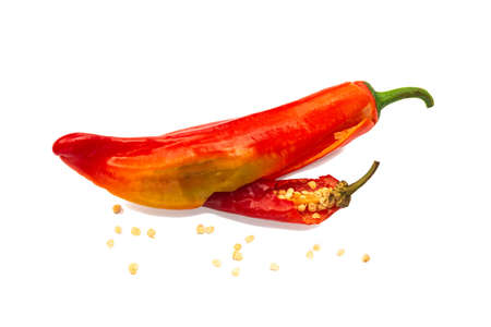 Two red chili peppers with seeds from within on a white background