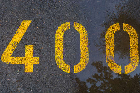 The number 400 is located on wet asphalt. There is a puddle on the asphalt.の写真素材