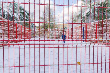 The basketball court, closed by a red fence, is covered with snow.の写真素材