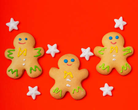 Christmas card featuring gingerbread men and white stars on a red background. New Year and Christmas...
