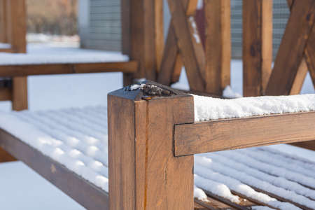 A brown wooden bench in a city park is covered with snow.の写真素材