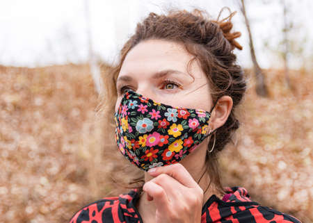 Beautiful thirty-year-old woman in colored mask outdoors.の写真素材