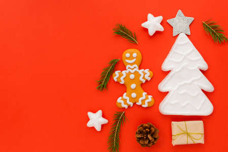A gingerbread man is located on a red background along with gifts and a Christmas tree. Christmas...