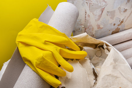 Old and new wallpapers, gloves are on the background of a dilapidated wall. DIY repair.の写真素材