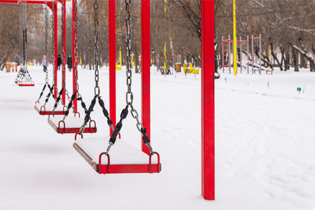 The children's swing is in the city winter park.の写真素材