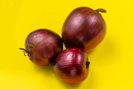Ripe fruits of red onion on a yellow background.の写真素材