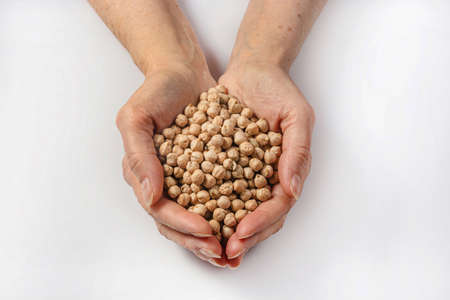 Woman holding garbanzo bean seeds in her palms on a white background.の写真素材