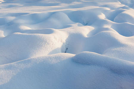 Snowy wavy texture with harsh blue shadows. Sunset.の写真素材