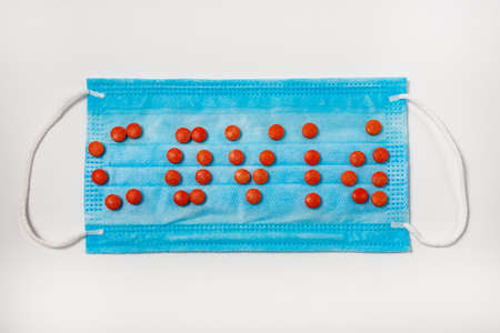 The inscription Covid - 19 and pills on the background of a medical mask. Flat lay. Copy space.の写真素材