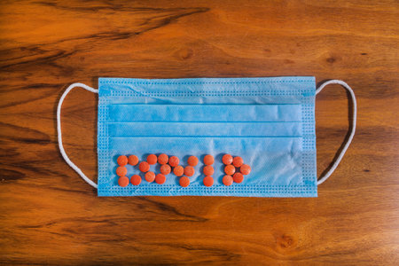On the blue medical mask is the word covid made of pills. Coronavirus concept.